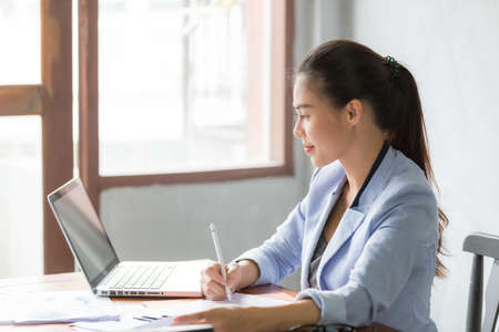 Business asian woman working at home and see information from laptop. Business, finance and technology concept.の写真素材