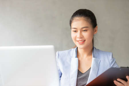 Business asian woman working at home and see information from laptop. Business, finance and technology concept.の写真素材