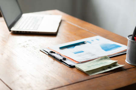 Office workplace with laptop and cash on wood table. Concept of rich with business.の写真素材