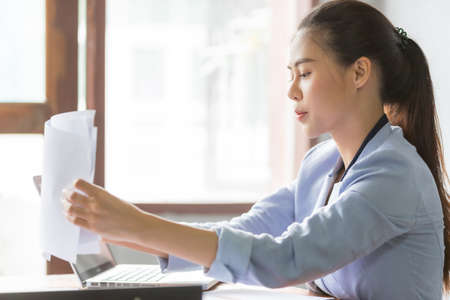 Business asian woman working at home and see information from laptop. Business, finance and technology concept.の写真素材