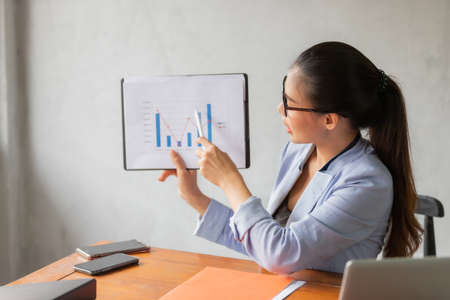 Business asian woman working at home and see information from laptop. Business, finance and technology concept.の写真素材
