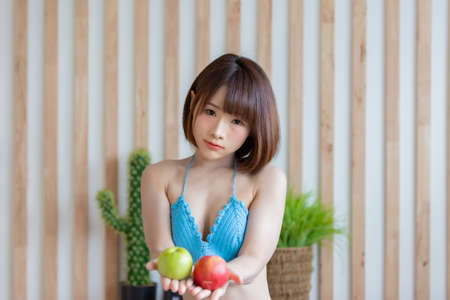 Portrait of young pretty sexy Asian woman wearing blue bikini in her room. Sexy girl feeling happy concept.の写真素材
