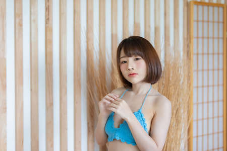 Portrait of young pretty sexy Asian woman wearing blue bikini in her room. Sexy girl feeling happy concept.の写真素材