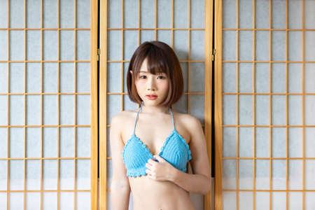 Portrait of young pretty sexy Asian woman wearing blue bikini in her room. Sexy girl feeling happy concept.の写真素材