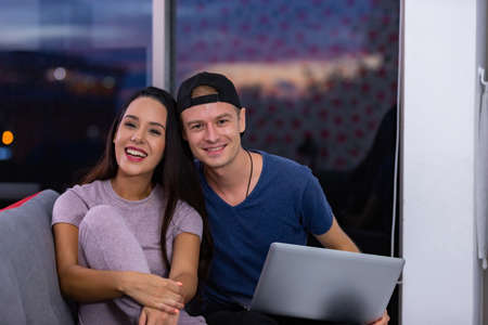 Young couple relaxing and enjoying at home on sofa with laptop. Concept happy couple.の写真素材