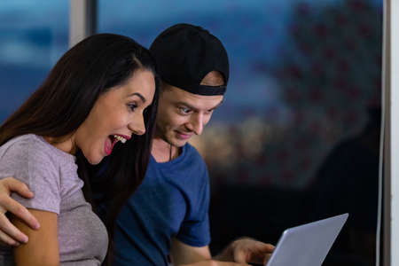 Young couple relaxing and enjoying at home on sofa with laptop. Concept happy couple.の写真素材