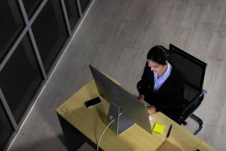 Asian young woman wearing headphone headset working overtime late at night in call center office. Concept top view for business at night.の写真素材