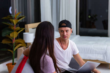 Young couple relaxing and conversation at home on sofa with laptop.の写真素材