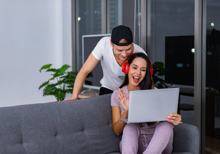 Romantic couple VIDEO call with feeling happy in their living room by using laptop computer.の写真素材