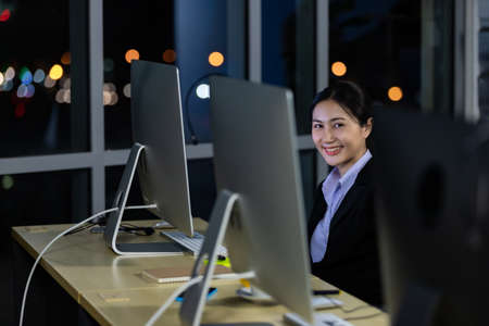 Portrait business young woman working overtime late at night in call center office. Concept for business at night.の写真素材