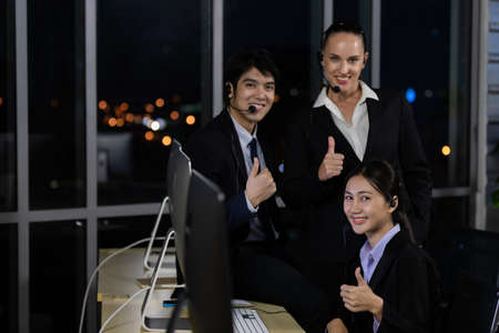 Business team working overtime late at night in call center office for support customer by online and phone. Concept for business at night.の写真素材