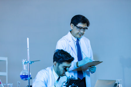 Team of research scientists analysing test trial new generation vaccine data. They work in a modern laboratory/ Medical center.の写真素材