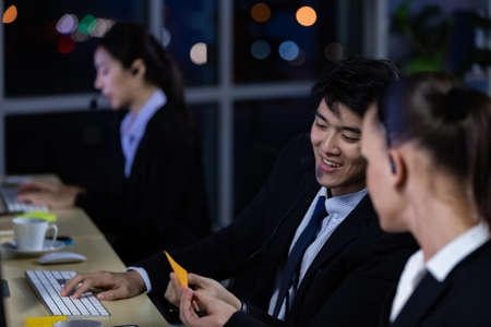 Businessman talking with team and working overtime late at night in call center office. Concept for business at night.の写真素材