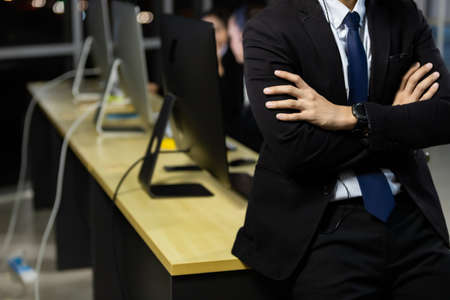 Businessman wearing headphone headset working overtime late at night in call center office with colleague team. Concept for business at night.の写真素材