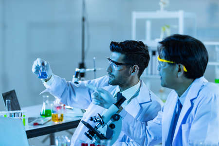 Team of research scientists analysing test trial new generation vaccine data. They work in a modern laboratory/ Medical center.の写真素材