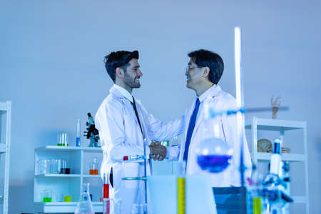 Two scientists shaking hands positivity success happiness. Concept collaboration between Caucasians and Asians scientists.の写真素材