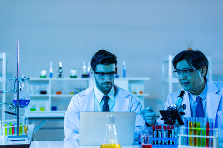Team of research scientists analysing test trial new generation vaccine data. They work in a modern laboratory/ Medical center.の写真素材