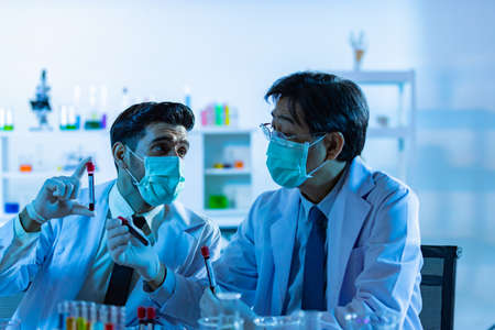 Team of research scientists analysing test trial new generation vaccine data. They work in a modern laboratory/ Medical center.の写真素材