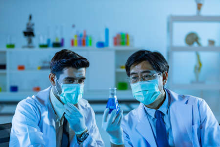 Team of research scientists analysing test trial new generation vaccine data. They work in a modern laboratory/ Medical center.の写真素材