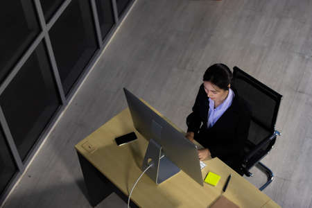 Asian young woman wearing headphone headset working overtime late at night in call center office. Concept top view for business at night.の写真素材