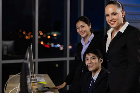 Business team working overtime late at night in call center office for support customer by online and phone. Concept for business at night.の写真素材