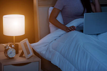 Woman in bed at home bedroom working concentrated with the laptop at night or using the internet...