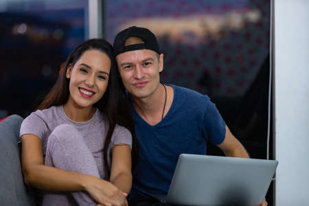 Young couple relaxing and enjoying at home on sofa with laptop. Concept happy couple.の写真素材