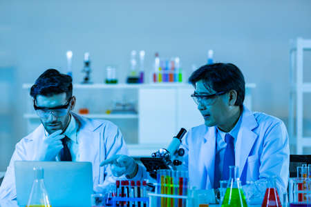 Team of research scientists analysing test trial new generation vaccine data. They work in a modern laboratory/ Medical center.の写真素材