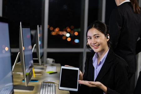 Portrait of smiling asian woman holding digital tablet for presentation work in office at night.の写真素材