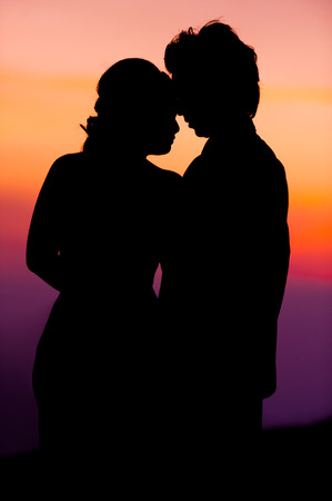 Silhouette of Embracing Asian Bride and Groom at Sunsetの写真素材