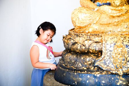 Little Girl doing gild on buddhism statueの写真素材