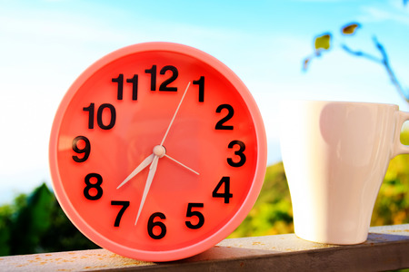 alarm clock on natural landscape season park with coffee cup