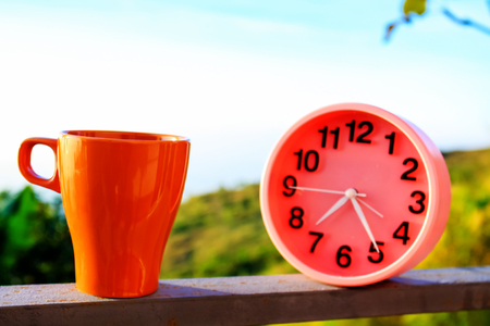 alarm clock on natural landscape season park with coffee cup