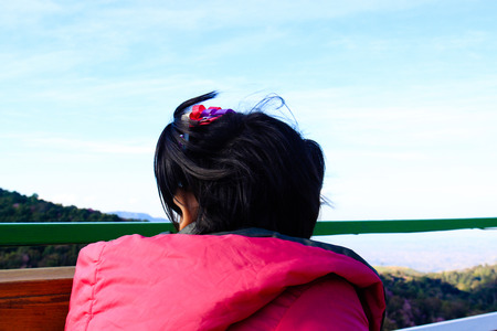 Portrait of cute little girl sitting on wooden bench outdoors.の写真素材