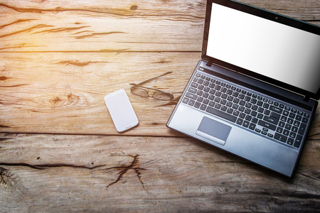 Top view laptop smart phone and glasses with sunset on the wood floorの写真素材
