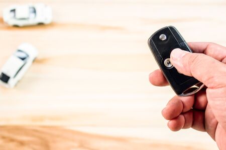 Hand a man press remote control for key lock door car for security concept car model on the wood floorの写真素材