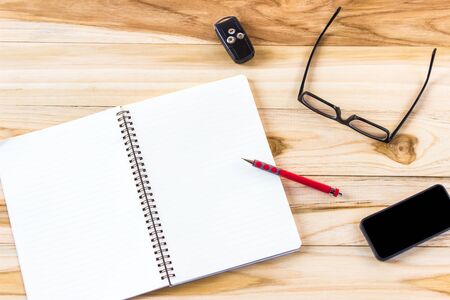 à¹Notebook glasses key of car smart phone pencil on the wood table background for business conceptの写真素材
