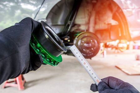 Hand a man use steel ruler check and adjust level screw of shock absorber spring and car maintenance  background  in garage modify concept and performance of carの写真素材