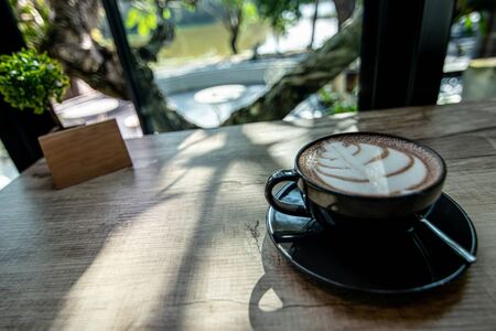 Soft focus of Hot coffee mug on wood table and Nature view in Rural village and sunlight in coffee shopの写真素材