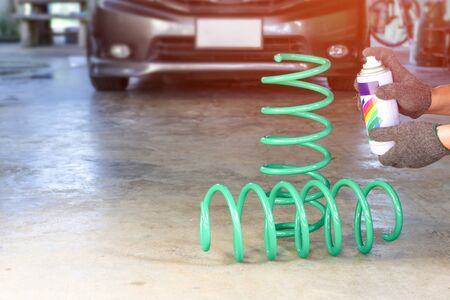 Technician man repair paint of Spring suspension  In the garage and blur car background for texture...