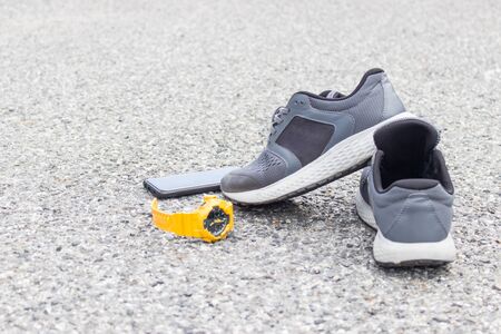 Close up running sport shoes smart phone and clock sport on the asphalt road  for walking and running safety concept prevent injury from exercise in relax day and industry backgroundの写真素材