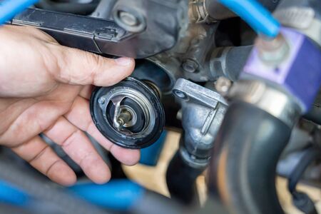 Hand a technician take of Car thermostat in engine room and check water heating of car for maintenance concept の写真素材