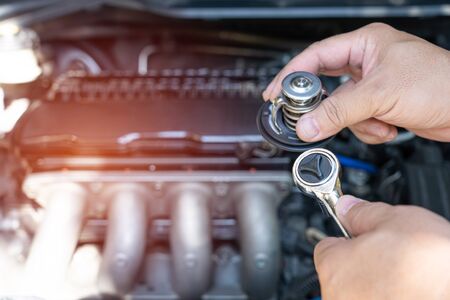 Hand a technician take of Car thermostat in engine room and check water heating of car for maintenance concept の写真素材