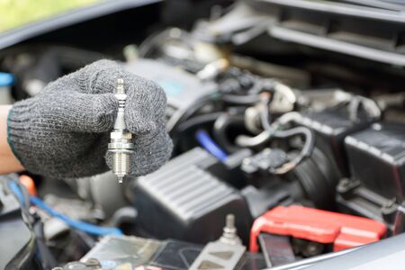 Car spark plug in a hand of Technician and engine room blur background service conceptの写真素材