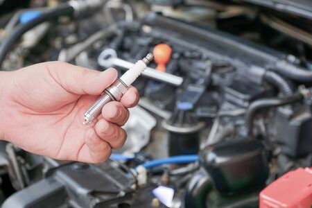 Car spark plug in a hand of Technician and engine room blur background service conceptの写真素材