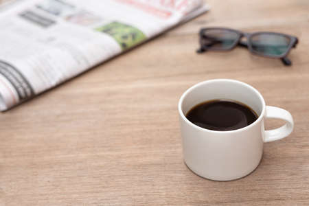 Coffee cup glasses and newspaper on wood table Reading news in the traditional world no Social networkの写真素材