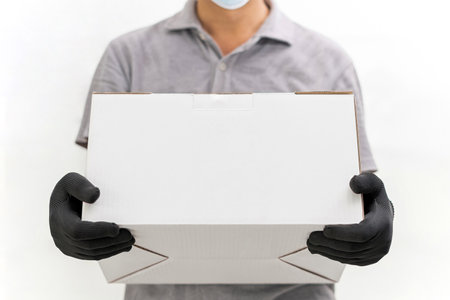 Man use hand to lift the shopping box wearing gloves and protective mask for protection in delivery work with white cement wall backgroundの写真素材