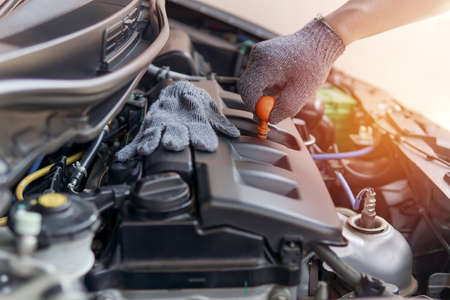 Mechanic checking engine oil level in engine room  in auto car repair service center,service photo...