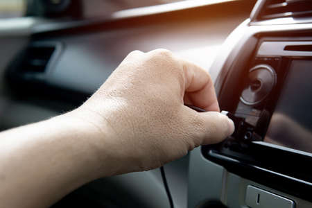Hand a man plug in USB cable on the car audio use connecting data car play and music Navigation...