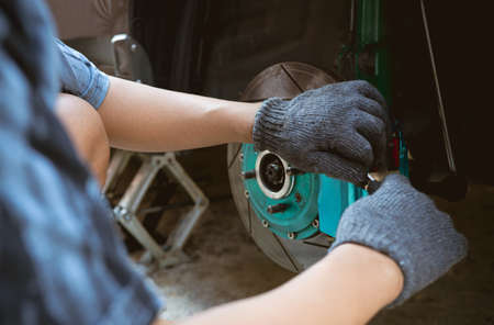 Close up brake caliper of car and a man use L wrench remove bolt of pad brake in maintenance car conceptの写真素材